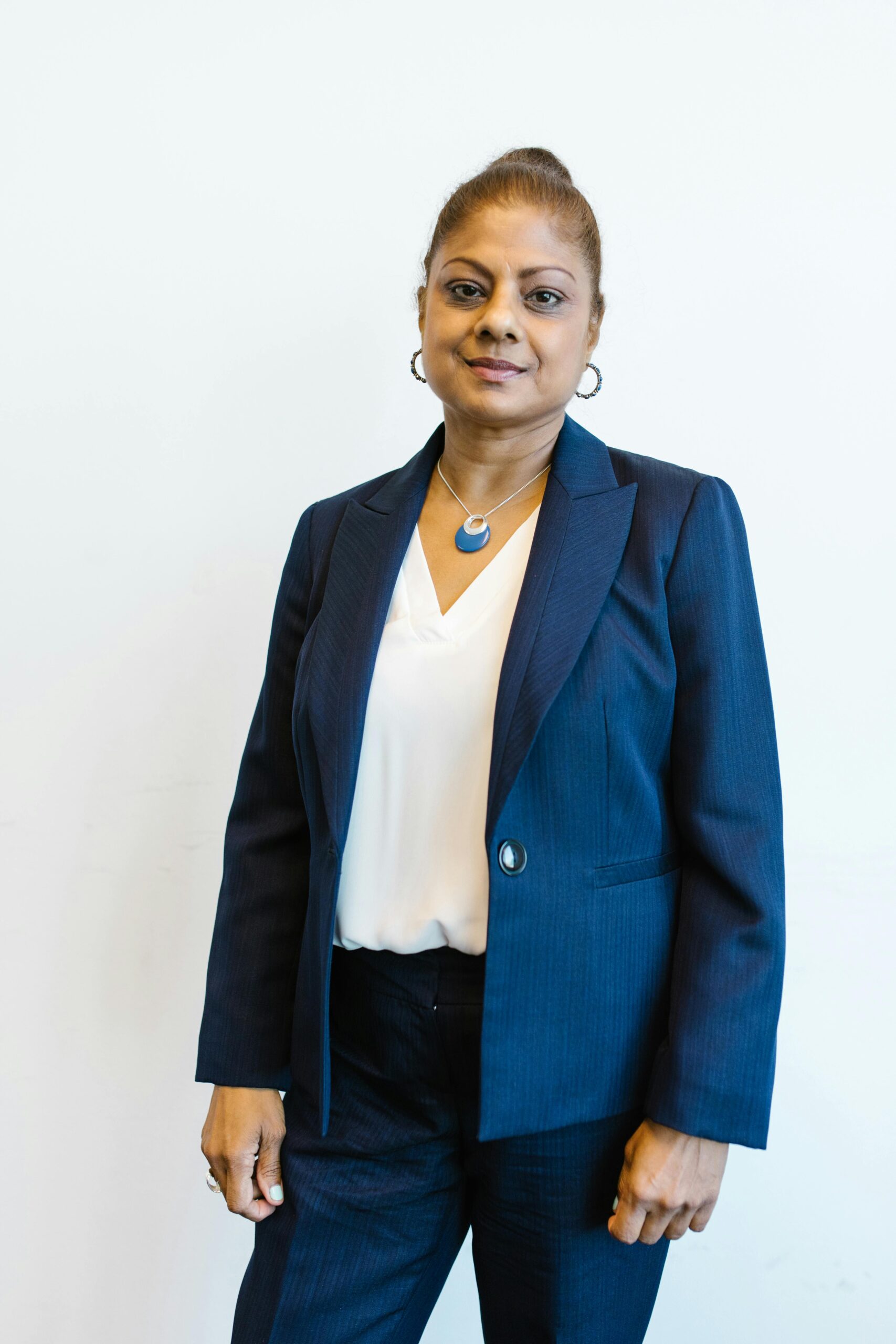 Confident woman in business attire smiling against a plain background.